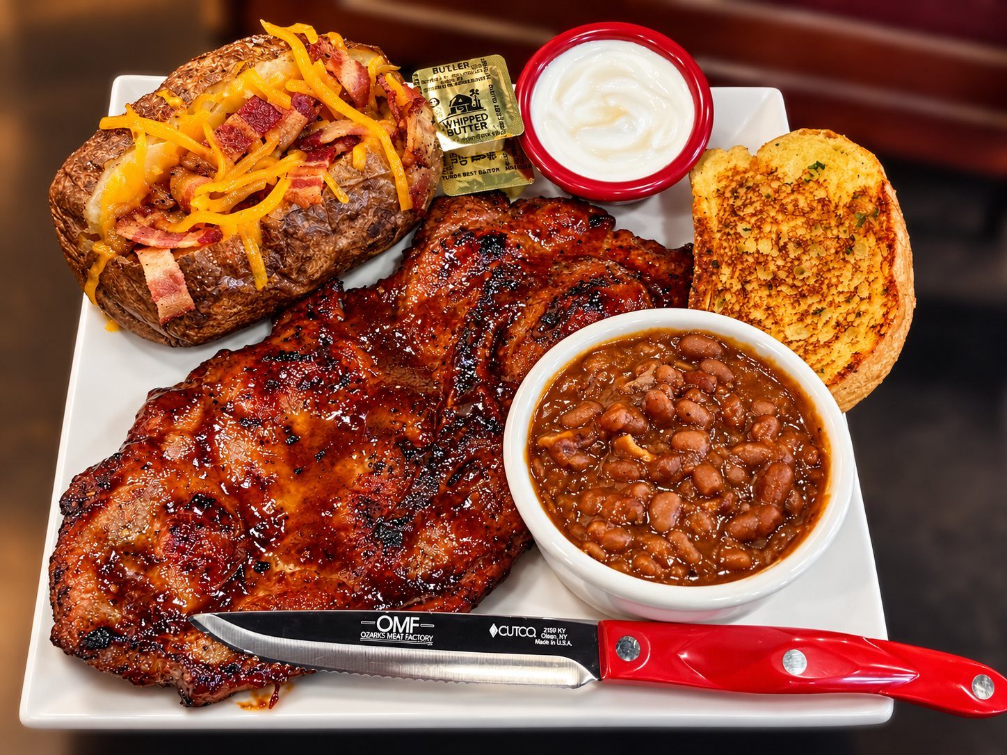 Pork steak plate with loaded baked potato, baked beans and garlic toast