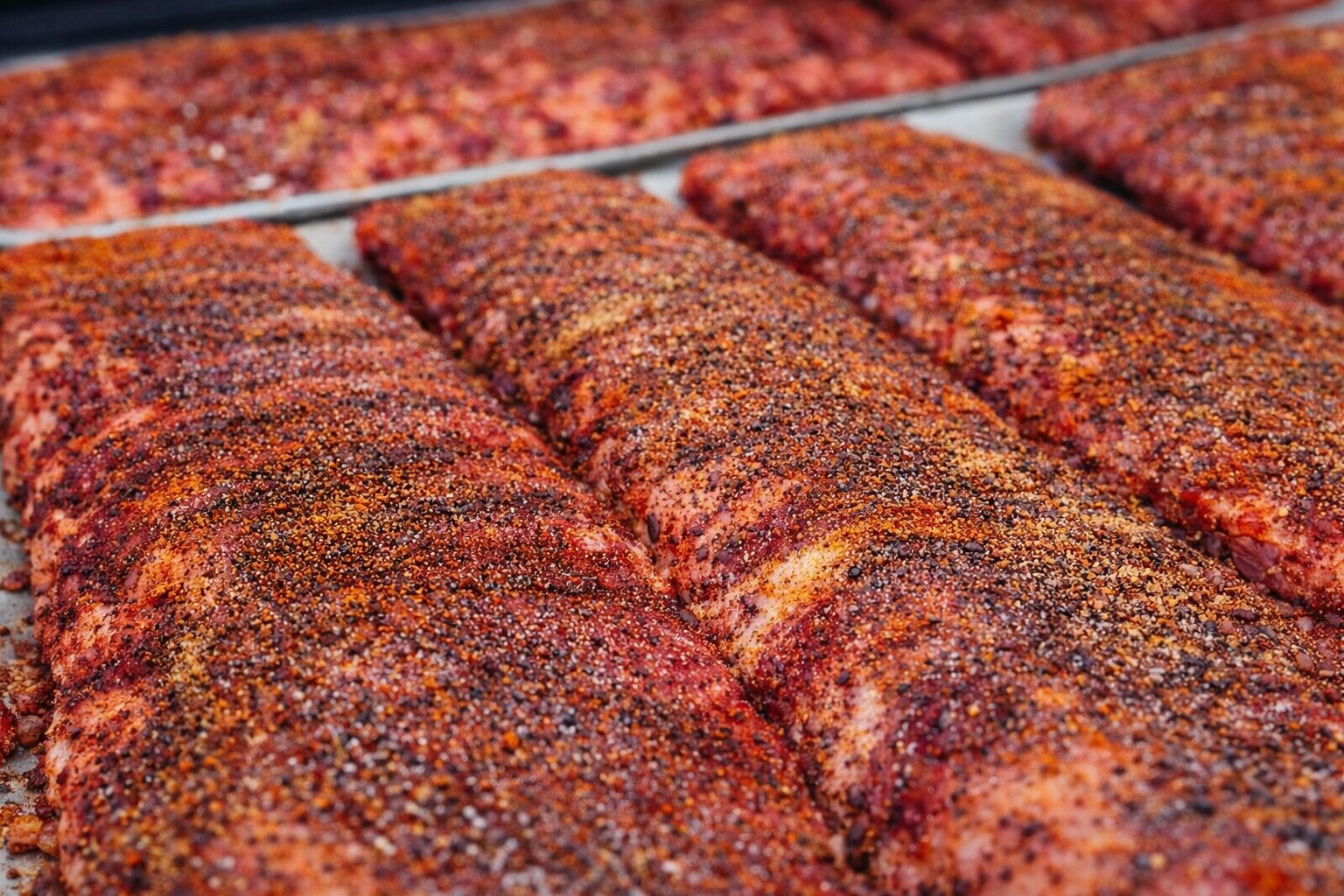 Racks of seasoned ribs ready for the smoker
